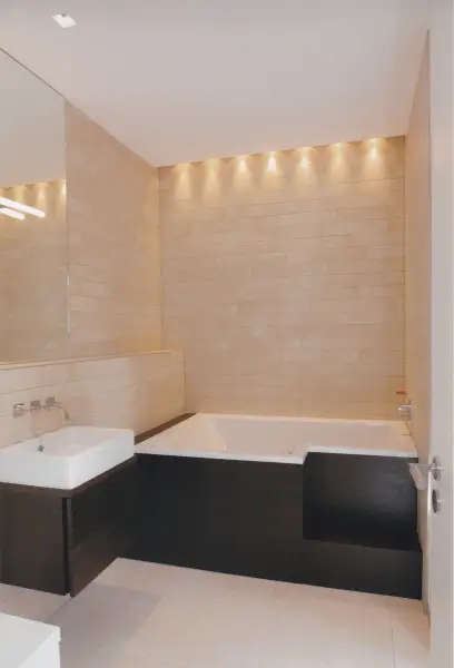 Modernes Badezimmer mit eingebauter Badewanne, wandhängendem Waschbecken und indirekter Beleuchtung an der Wand. Badsanierung Wiesloch