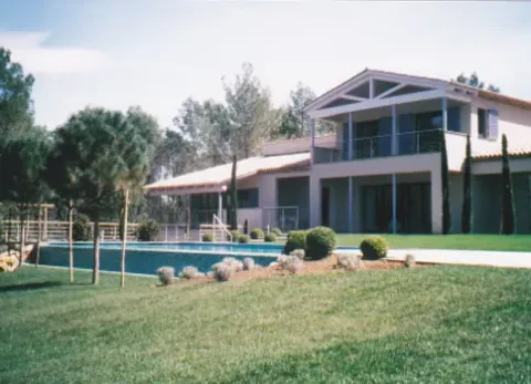 Moderner zweistöckiger Wohnhausbau mit großem Garten und rechteckigem Swimmingpool im Vordergrund.